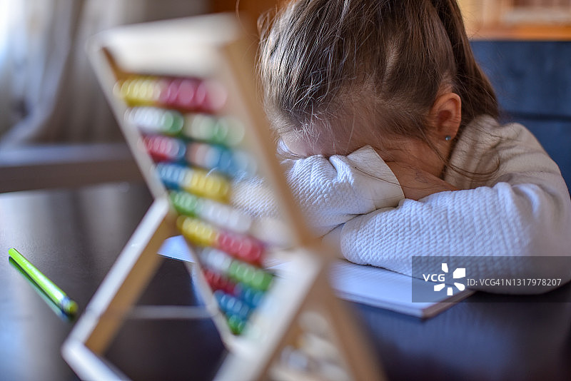 悲伤的孩子在算盘后哭泣，试图学习乘法表图片素材