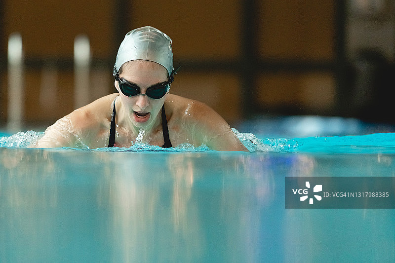 游泳池中白人成年游泳运动员的画像。专业运动员戴着泳镜在水中游泳图片素材