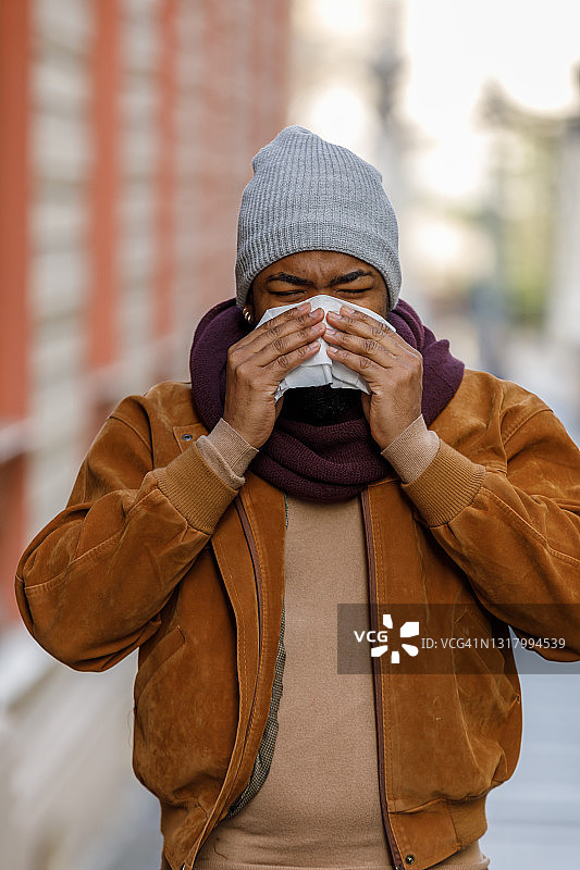 患流感和高烧的非洲裔男子在户外打喷嚏和咳嗽图片素材