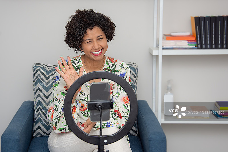 在三脚架上使用手机的女人图片素材