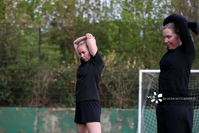 女足球员在足球场上伸展和热身图片素材