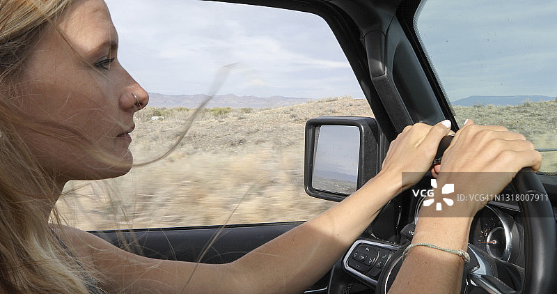 年轻女子驾驶越野车行驶在沙漠公路上图片素材