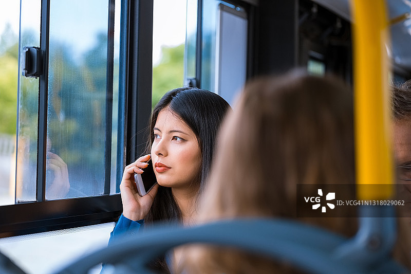 在公共汽车上用智能手机交谈的女人图片素材