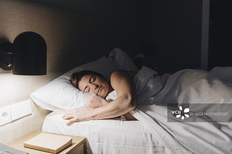 在酒店房间的床上睡觉的漂亮女人图片素材