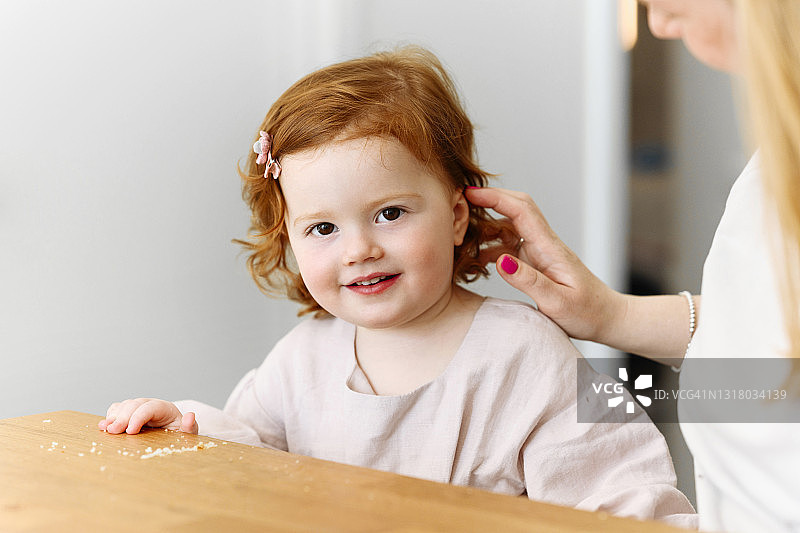 母亲在厨房的桌旁欣赏红头发的女儿图片素材