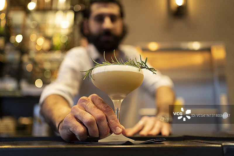 服务员在吧台递上百里香装饰的饮品图片素材