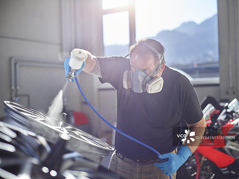 中年喷漆工在修理店用喷枪喷漆图片素材