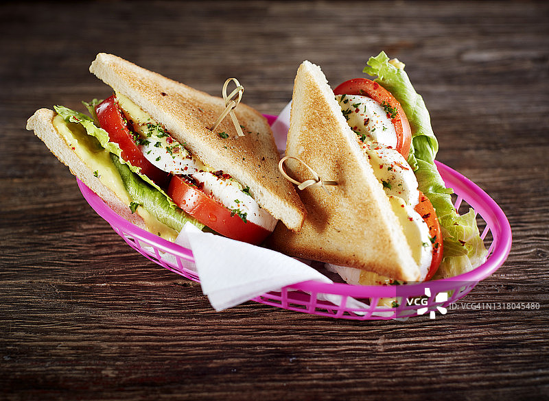 影棚拍摄：两份含卡普雷塞沙拉、番茄、马苏里拉奶酪和生菜的素食三明治图片素材