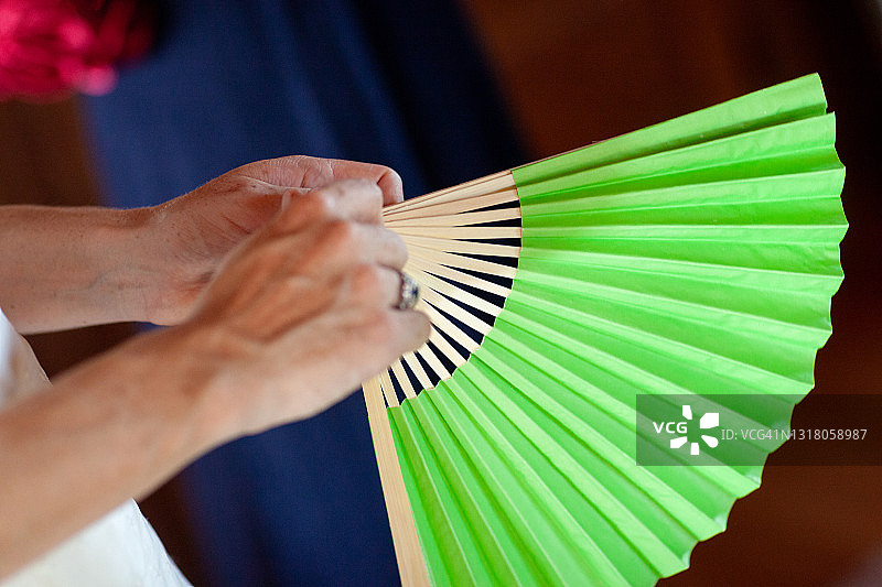 女性手持绿色打开的纸扇图片素材