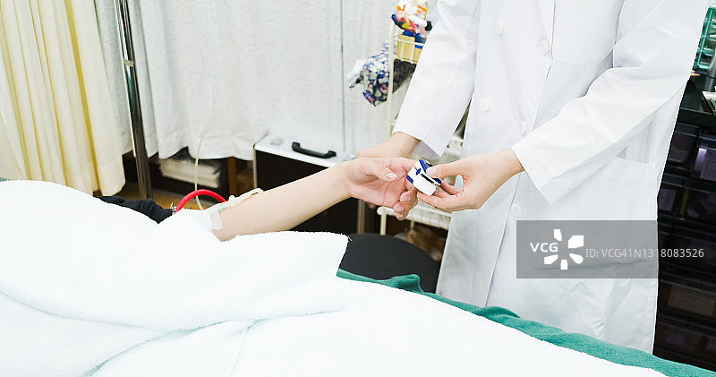 年轻的亚洲女医生使用脉搏血氧仪测量病人的身体状况图片素材