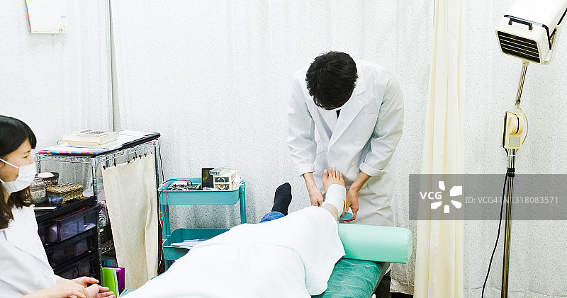 亚洲男医生为病人包扎脚踝图片素材