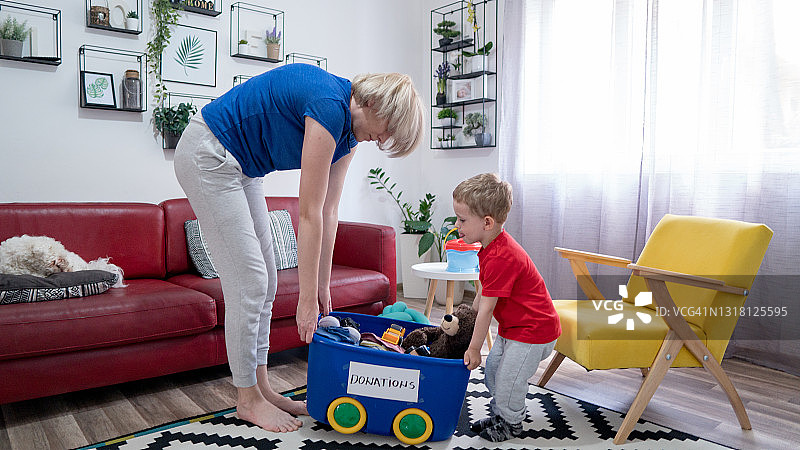 母子将衣服和玩具打包到捐赠箱里图片素材