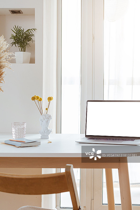 办公桌内部带空白白色屏幕的笔记本电脑。时尚的工作场所模型。图片素材