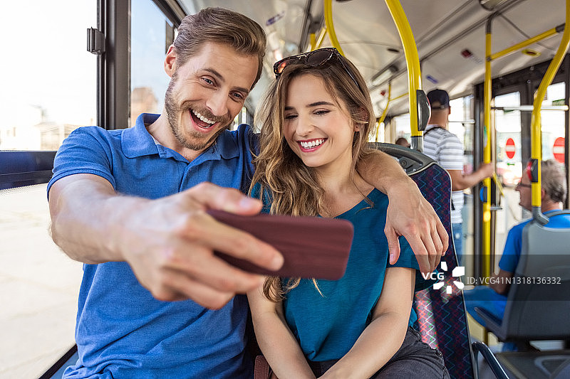 在公共汽车上自拍的微笑年轻情侣图片素材