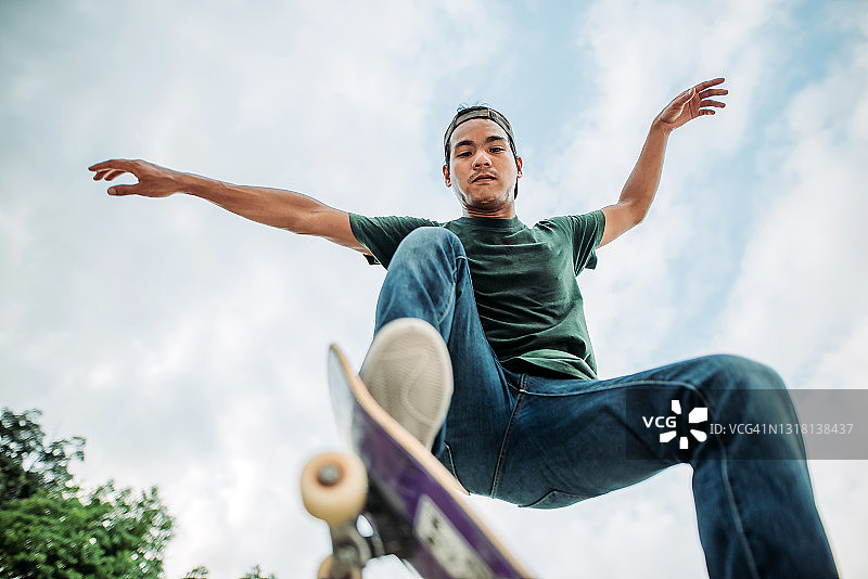 亚洲男子在滑板公园跳跃图片素材