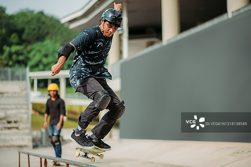 亚洲男子在滑板公园跳跃图片素材