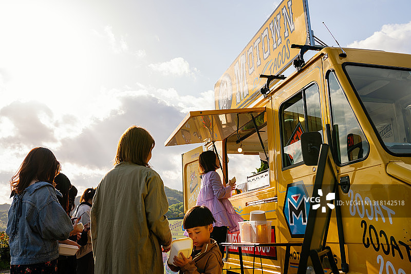 人们戴着口罩在餐车外保持社交距离排队图片素材