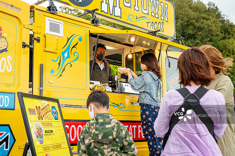 人们戴着口罩在餐车外保持社交距离排队图片素材