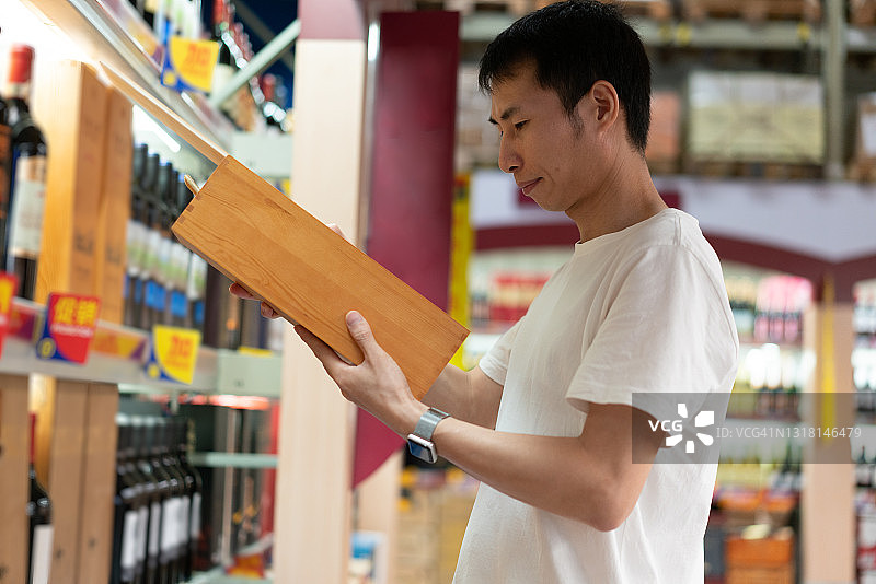 亚洲男人在商店购买红酒图片素材