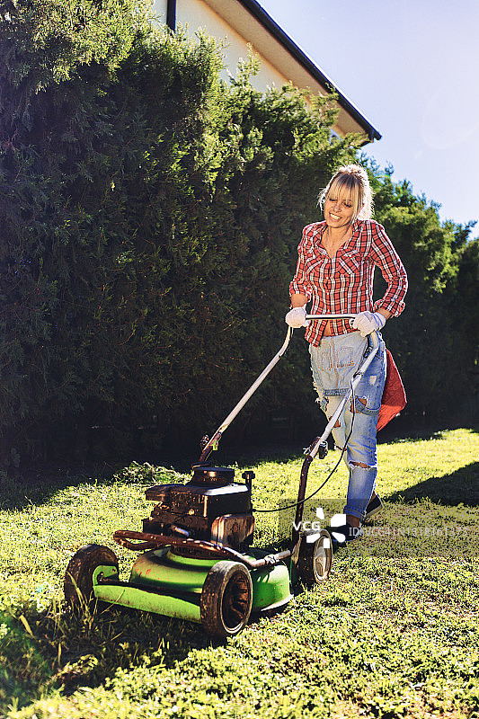 妇女在后院使用割草机图片素材