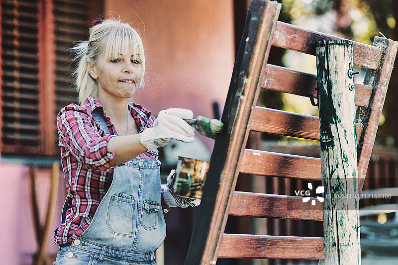 女人正在家里给栅栏上色图片素材