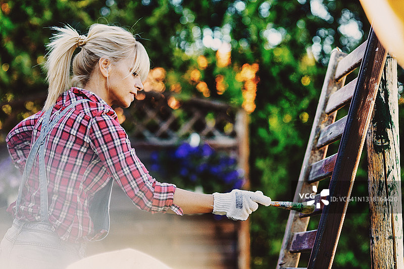 女人正在家里给栅栏上色图片素材