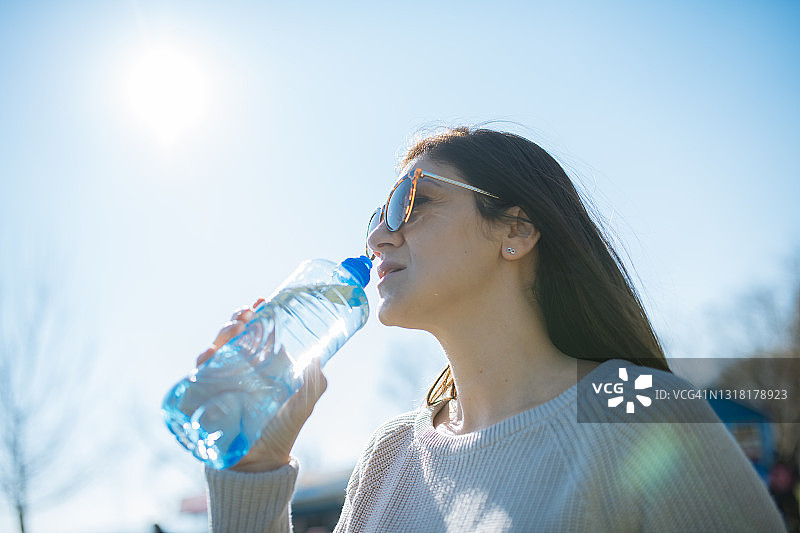 在户外喝塑料瓶装水的女人图片素材
