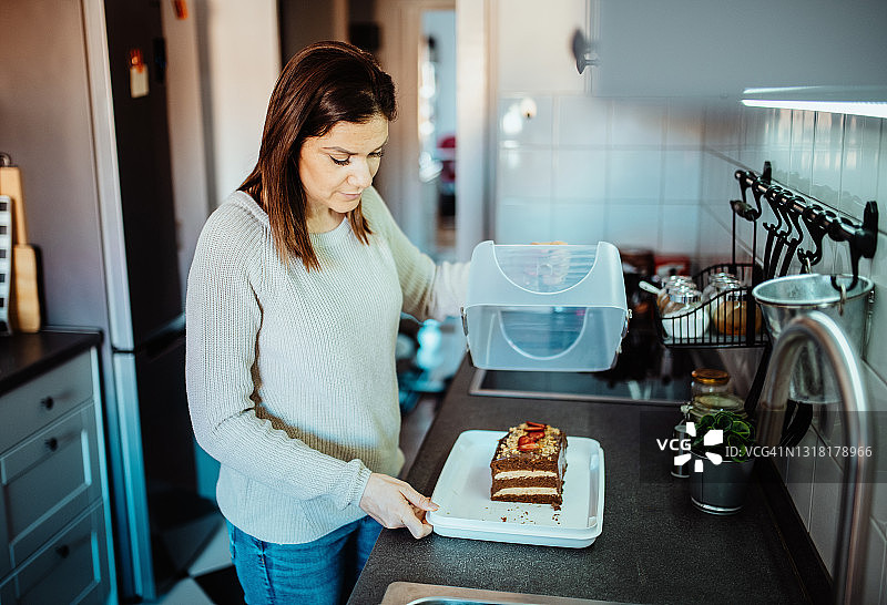 女人将蛋糕放入塑料容器图片素材