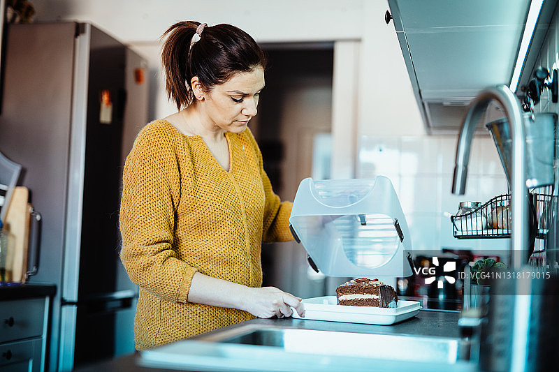 女人将蛋糕放入塑料容器图片素材