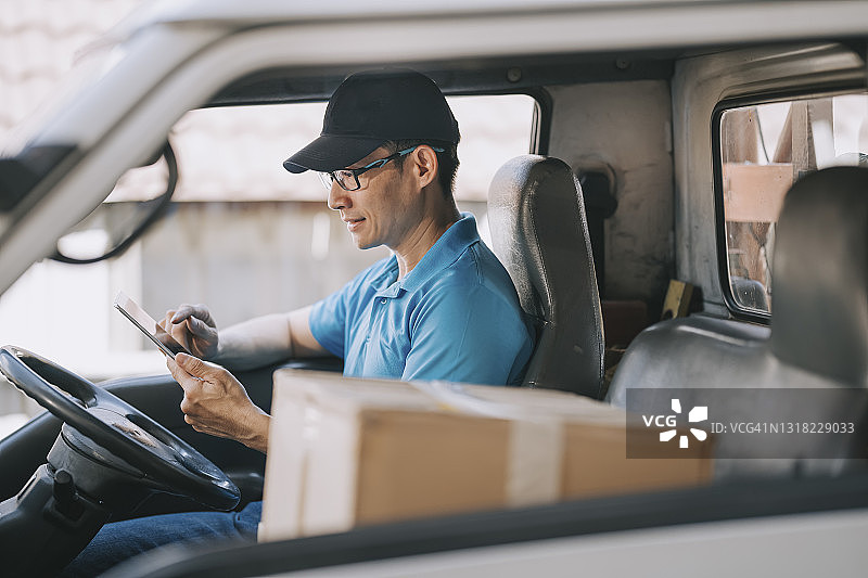 送货前，中国成熟男性送货员在车内使用平板电脑图片素材