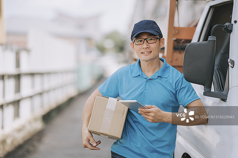 手捧纸箱看着镜头的亚洲华人送货员图片素材