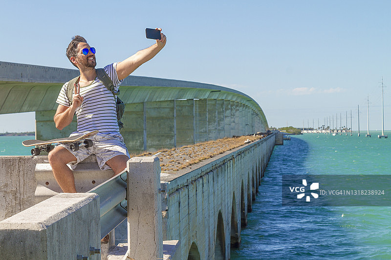年轻男子在佛罗里达州基韦斯特阳光明媚的夏日用智能手机自拍图片素材