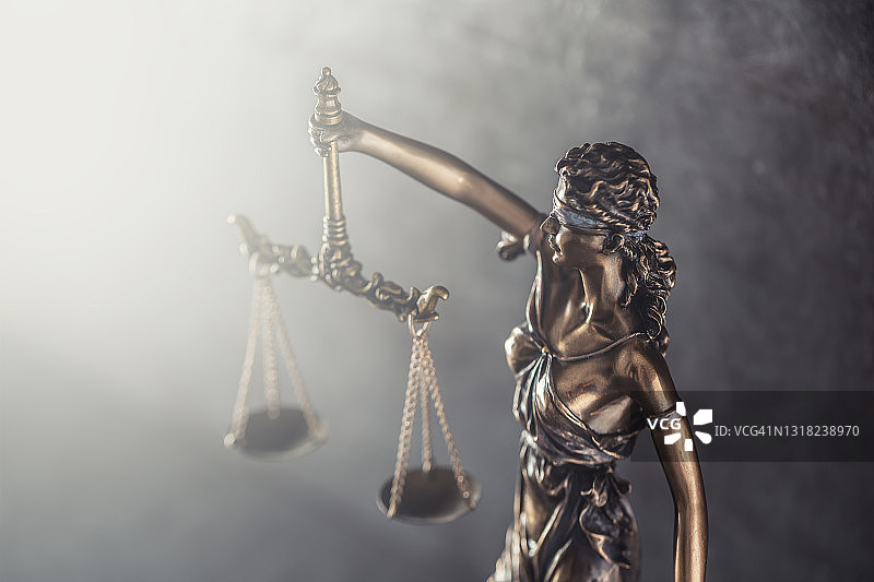 象征正义盲目的雕像，在光芒照耀下高举天平图片素材
