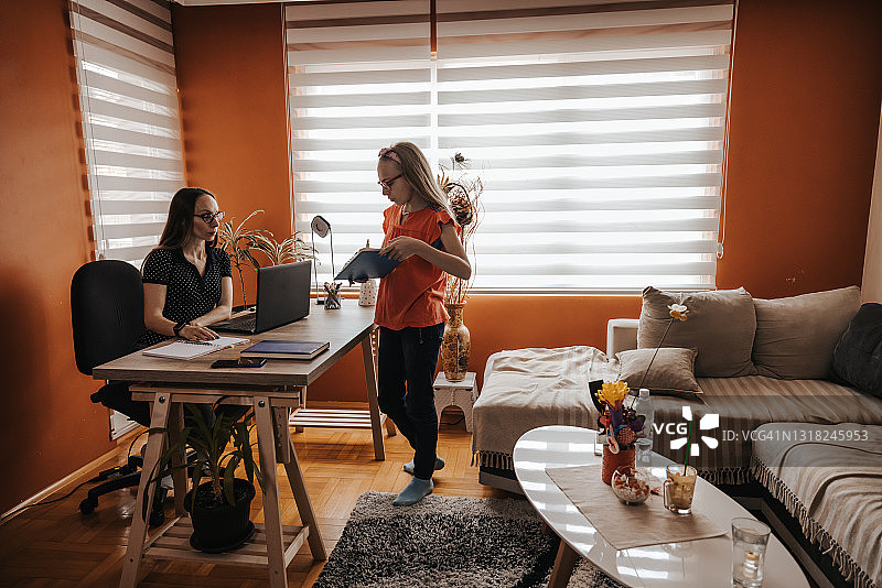 可爱的女儿在家庭办公室帮助母亲工作图片素材
