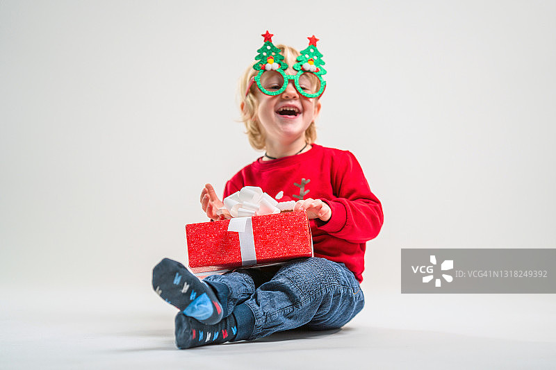 可爱的白人金发幼儿男孩拿着圣诞礼物看着镜头图片素材