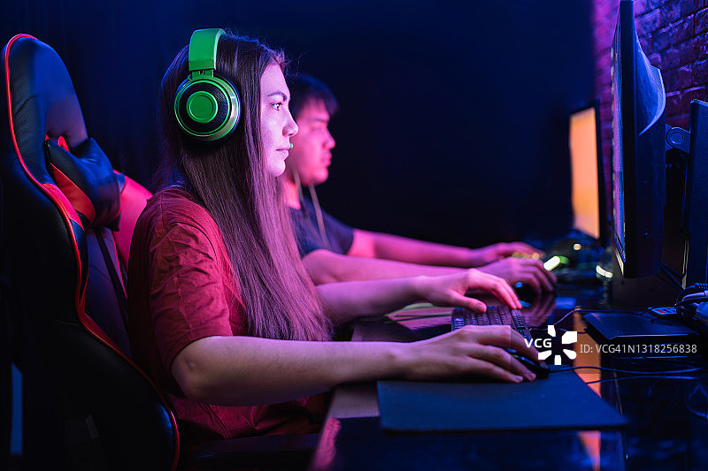 在霓虹灯下一起玩电脑游戏的男孩和女孩图片素材