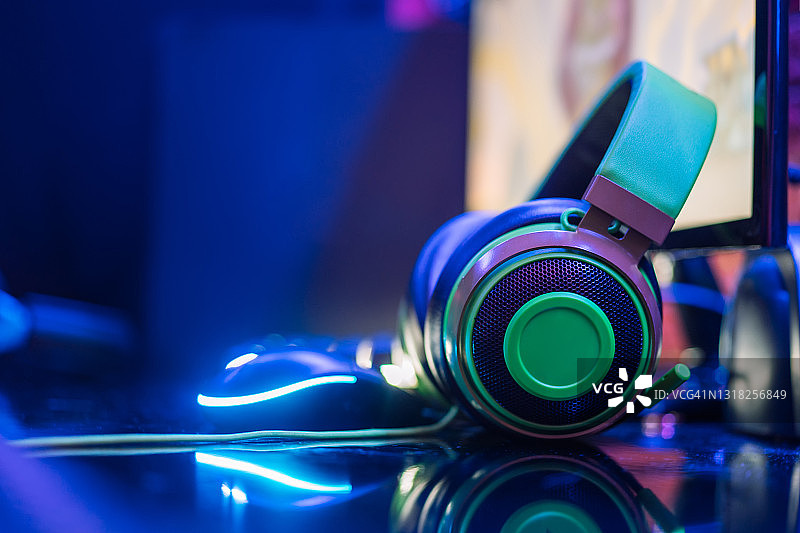 霓虹灯光下的绿色耳机和鼠标特写图片素材