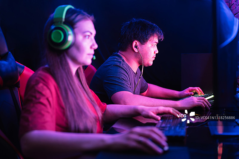 在霓虹灯下电脑俱乐部里玩耍的亚洲男人和女人图片素材