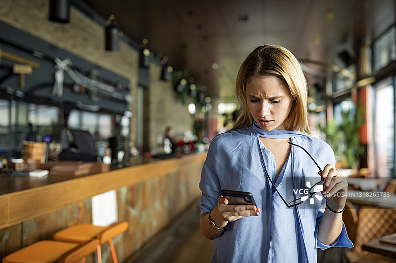 金发美女商务人士在咖啡馆使用手机图片素材