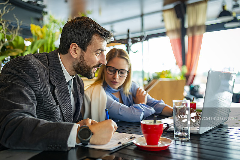 自信的年轻商业夫妇坐在现代咖啡馆里，进行在线研究以改善业务图片素材
