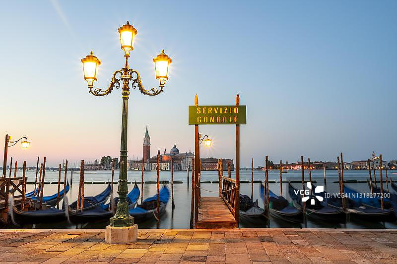 贡多拉服务船只停靠站，码头停靠着威尼斯贡多拉，后方是圣乔治马焦雷教堂，长时间曝光，威尼斯，威尼托，意大利图片素材