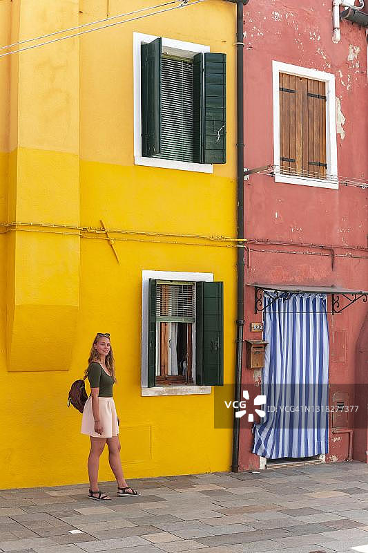 在意大利威尼斯布拉诺岛彩色房子前的年轻女人图片素材