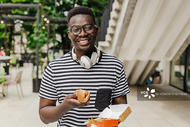 正在吃热狗的年轻非洲裔美国男子图片素材