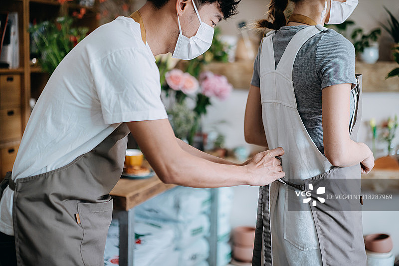年轻的亚洲情侣经营小型花店，佩戴防护口罩防止病毒，重新开业图片素材