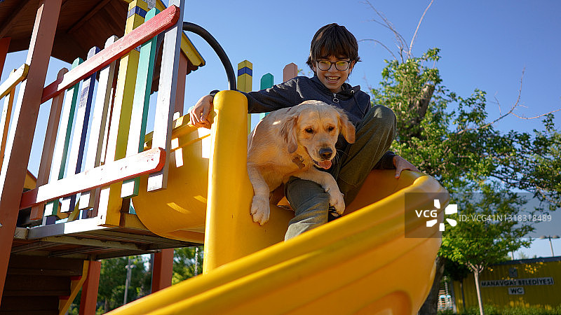 小男孩和狗在游乐场玩滑梯图片素材