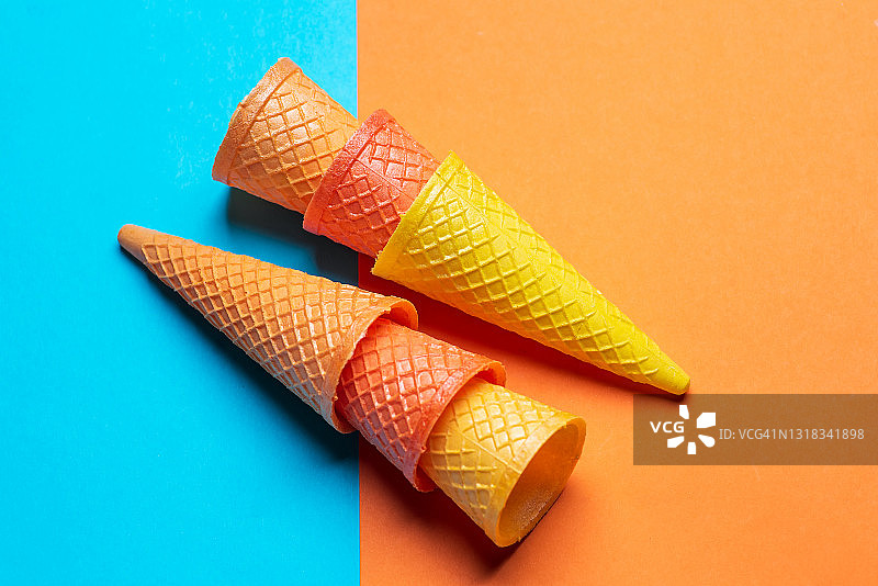 橙蓝色对比背景上的冰淇淋甜筒, 俯视扁平构图图片素材