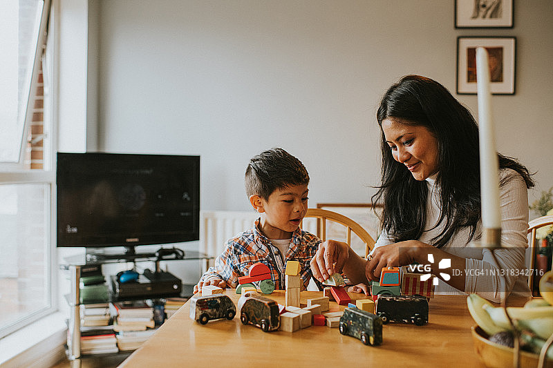 母子在餐桌旁玩木质积木图片素材
