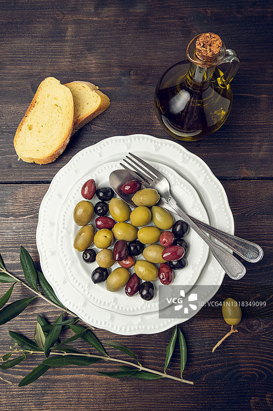 白色盘子里的黑色和绿色橄榄与橄榄油图片素材