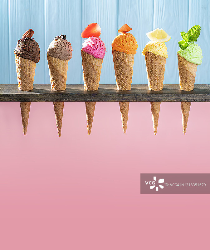 一排什锦冰淇淋蛋卷，粉色和蓝色木纹背景图片素材