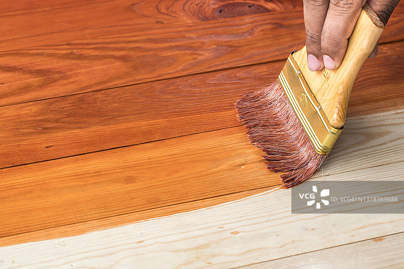 手持刷子在木质表面涂清漆图片素材
